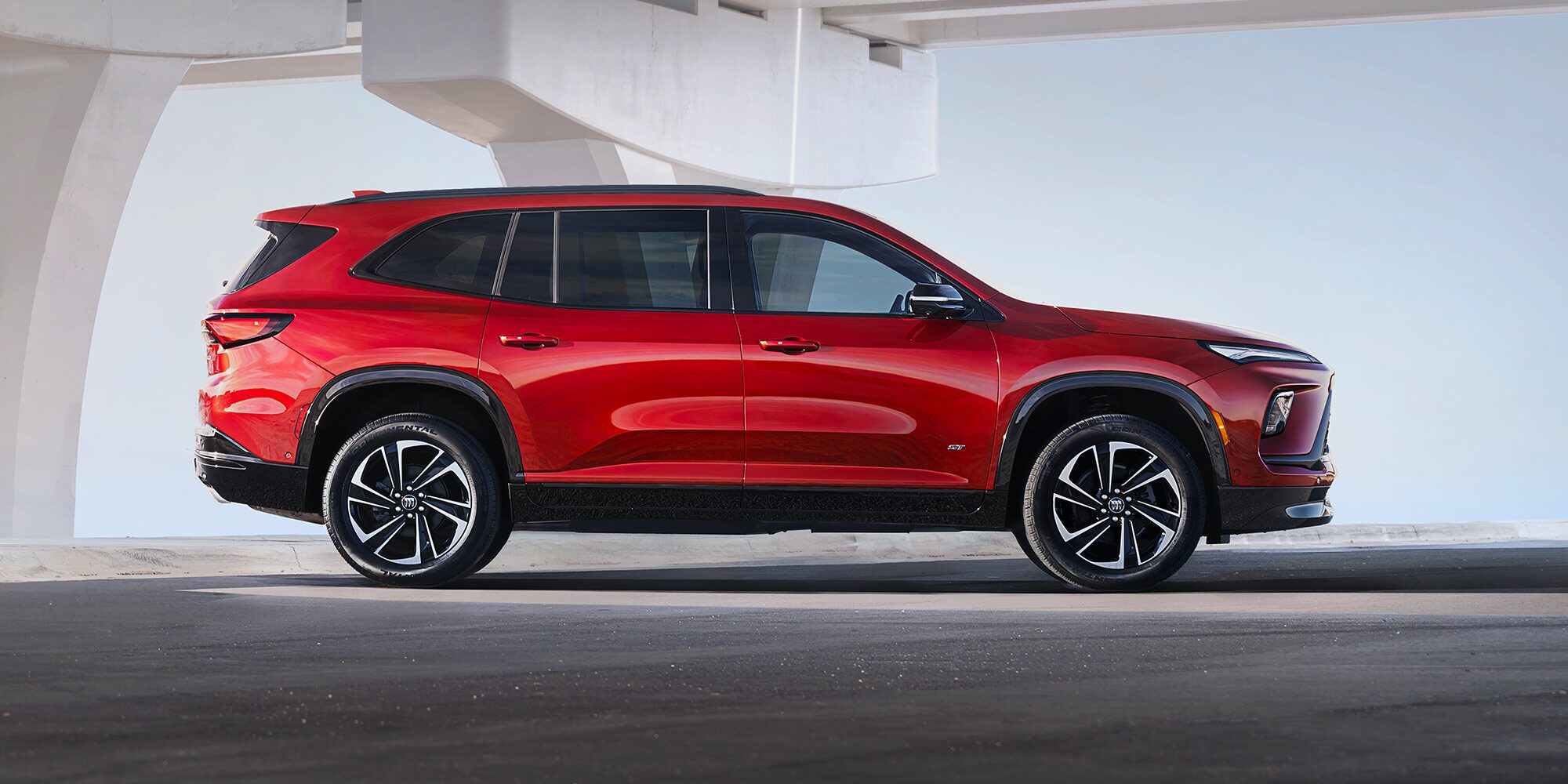 Red Buick Encore GX SUV Parked Under a Concrete Elevated Structure in a Minimalist Setting