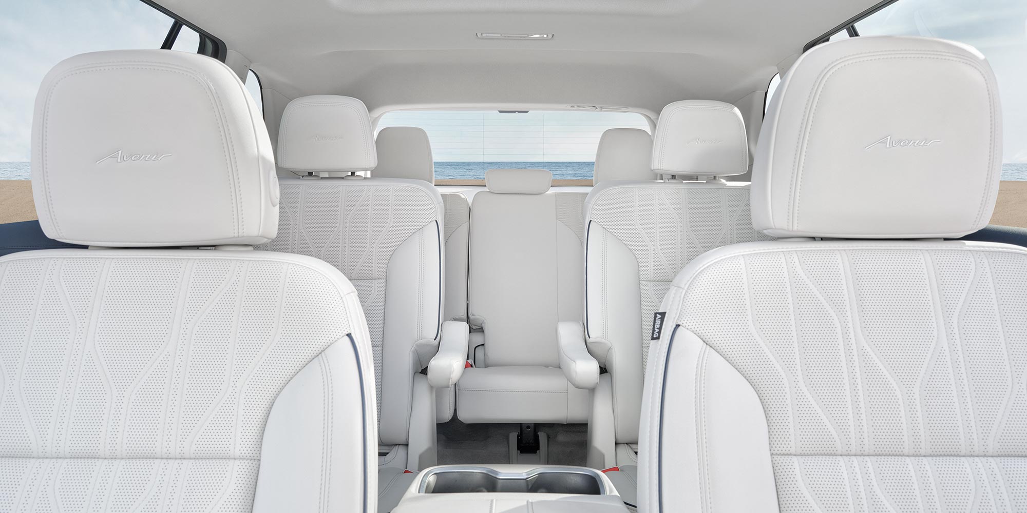 An Interior View of a Buick Avenir with White Leather Seats, a Panoramic Sunroof, and the Ocean Visible Through the Rear Window
