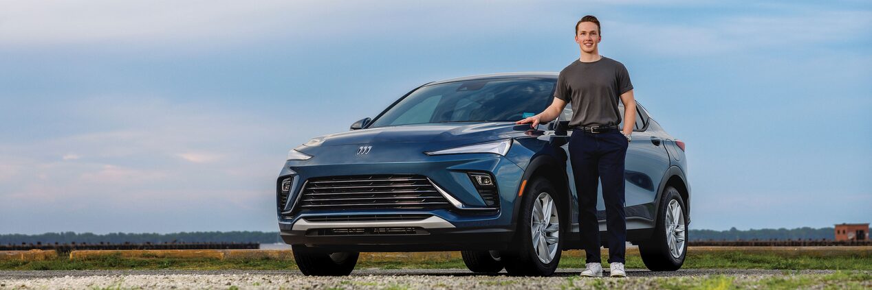 A Man Standing Next to a Parked Buick Envista