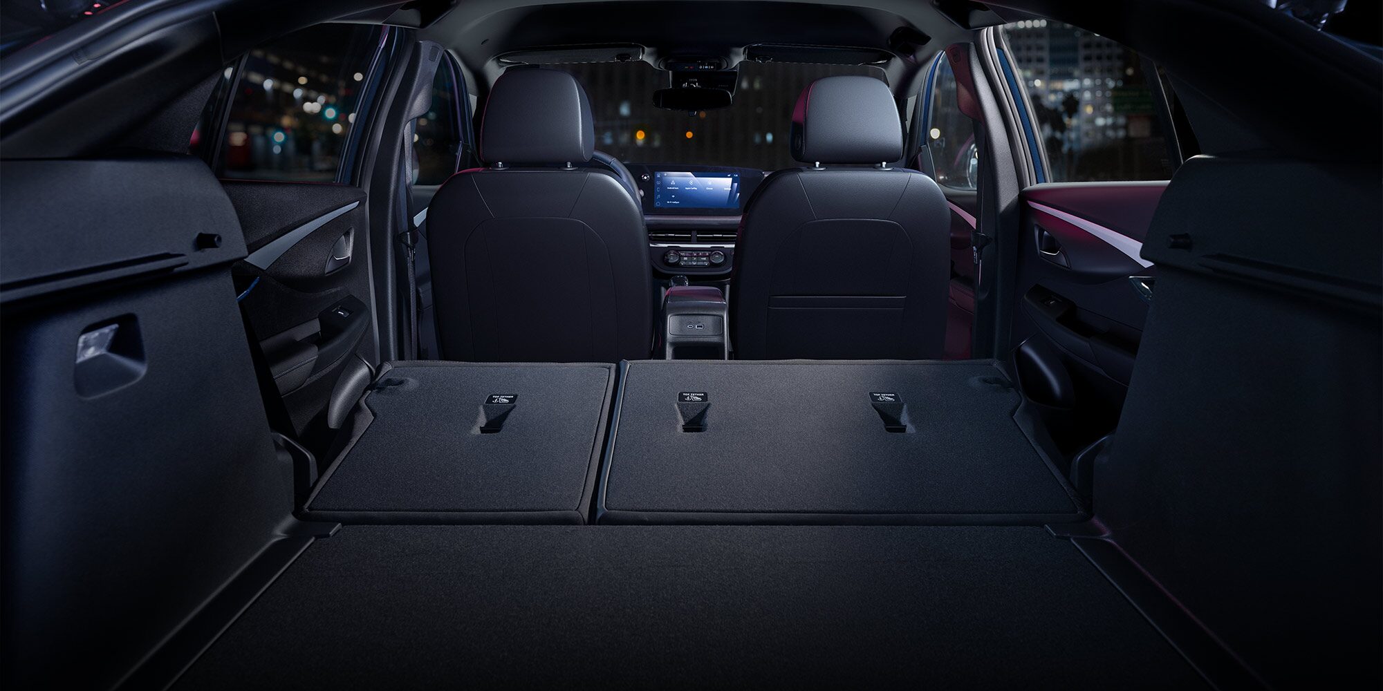 The Rear Interior of a 2026 Buick Envista with Seats Folded Down at Night in a City