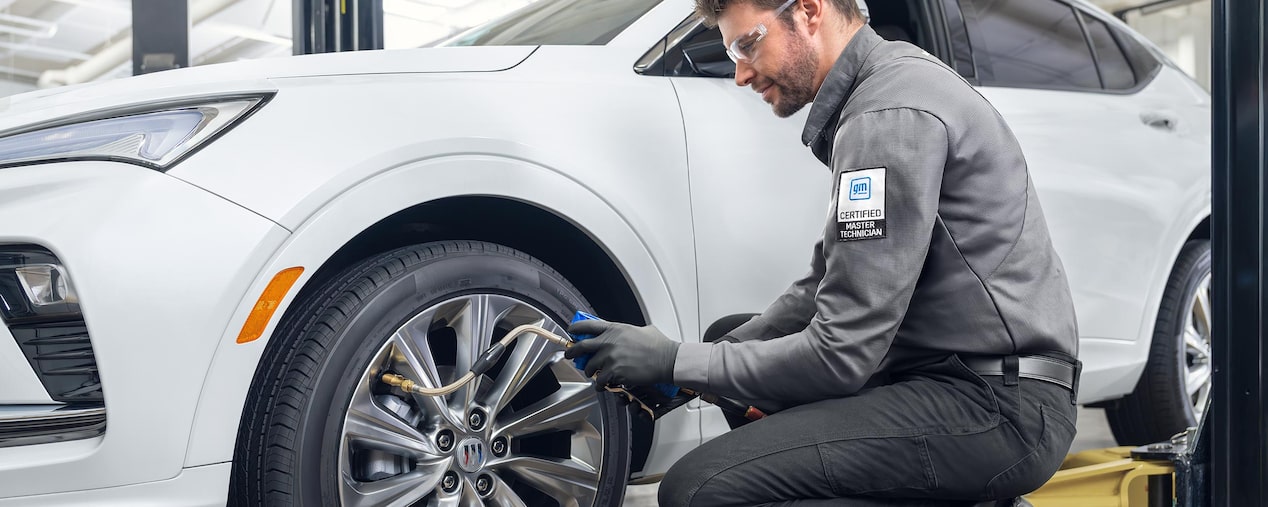 A Buick Certified Master Technician Checks the Tire Pressure on a White Buick SUV Wheel