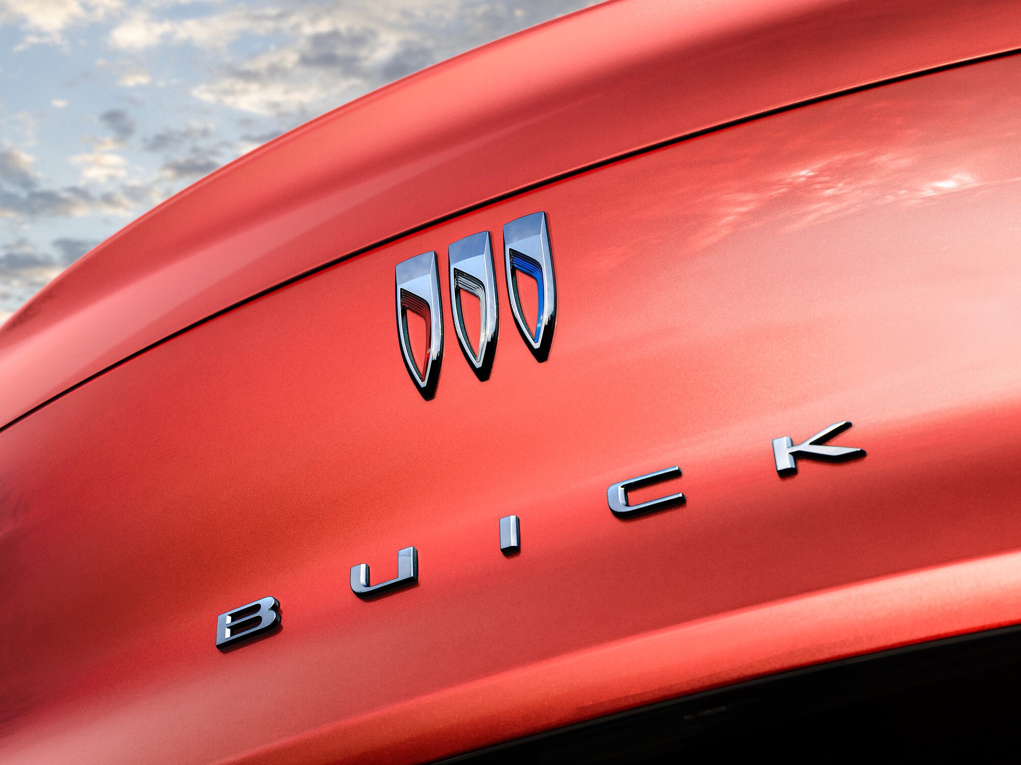 A Close-Up View of the Chrome Buick Logo and Wordmark on a Red Vehicle