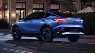 Rear Three-Quarters View of a Buick Envista Compact Crossover Driving Down a City Street at Night