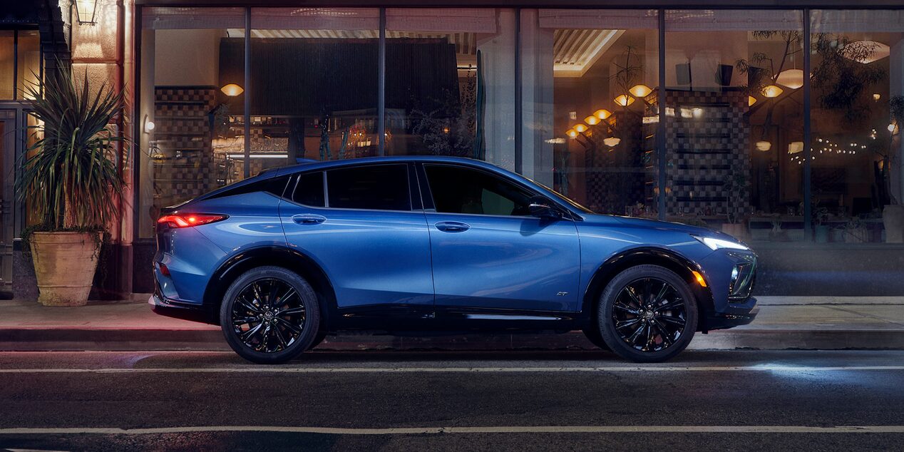 Profile View of a Blue Buick Envista Compact Crossover Parked at Night on a City Street