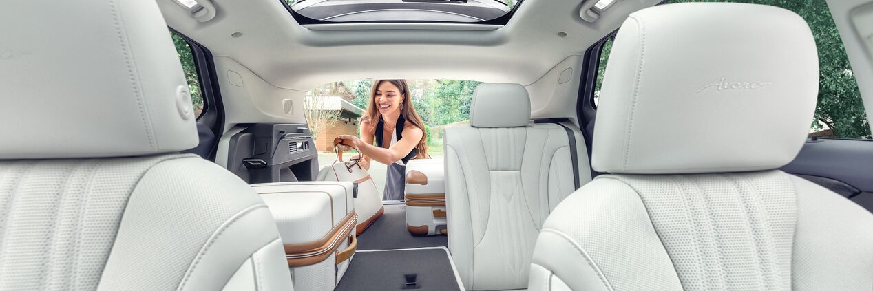 Interior View of a 2025 Buick Envision 5 Passenger SUV with a Person Loading Luggage Into the Trunk