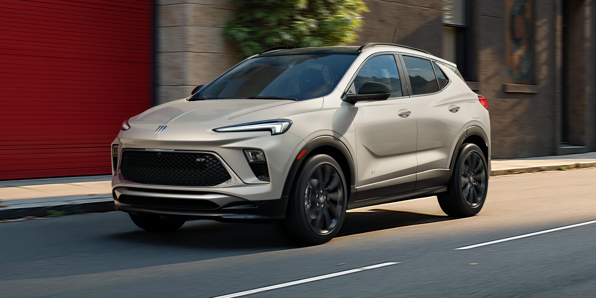 The 2026 Buick Encore GX Sports Touring SUV in the Color Ceramic Driving Down a City Street