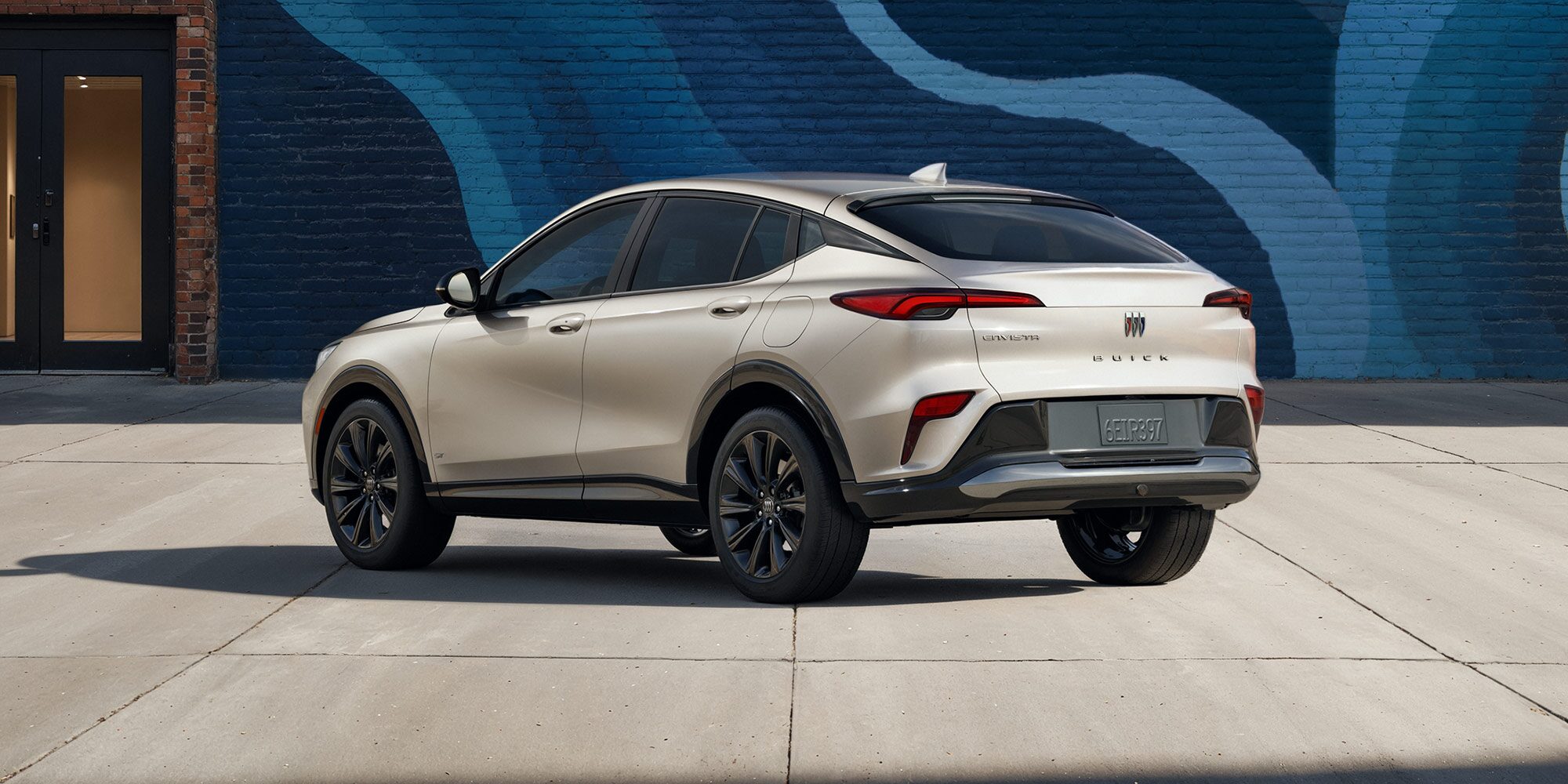 Rear View of the 2026 Buick Envista ST SUV Parked Next to a City Building Covered with a Colorful Abstract Mural