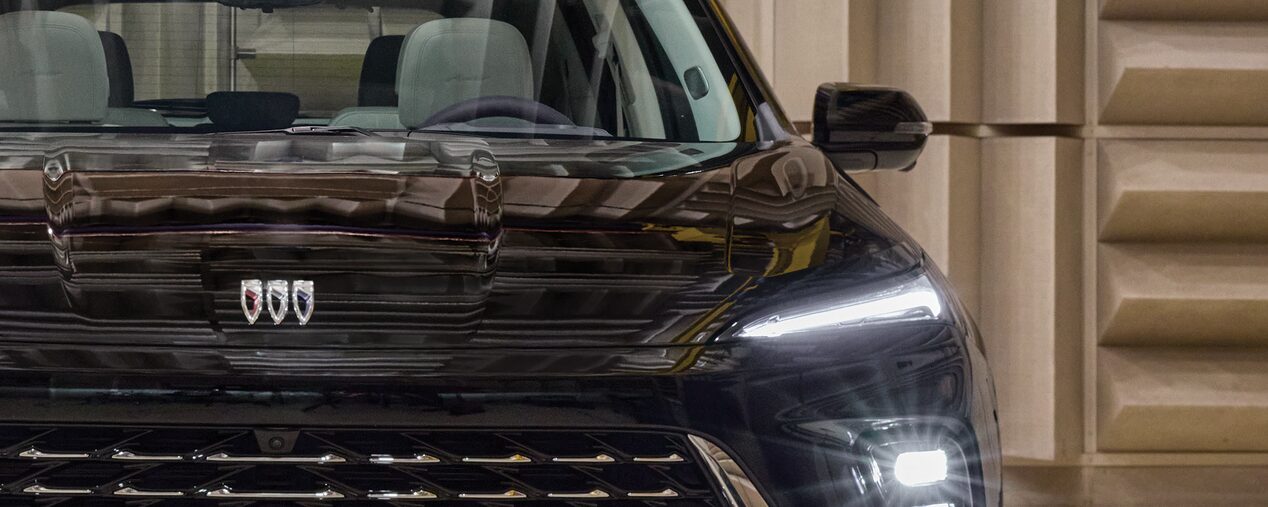 The Front of a Black Buick SUV with Headlights On in a Sound Testing Laboratory