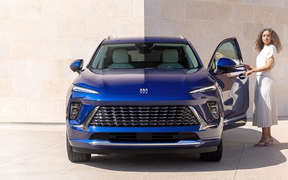 Woman Standing Next to a Blue Buick SUV Holding the Driver's Side Door Open