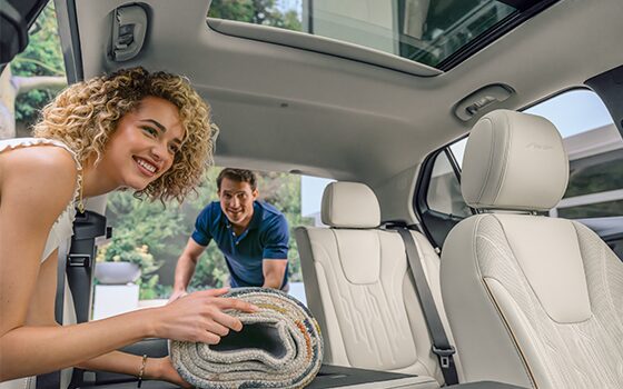 Man and Woman Holding a Rolled Up Rug Inside a White Interior Vehicle