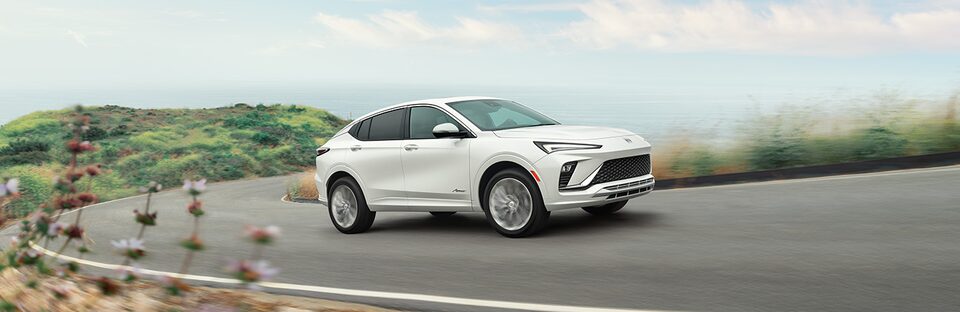 White Buick SUV Driving Uphill on a Curved Road