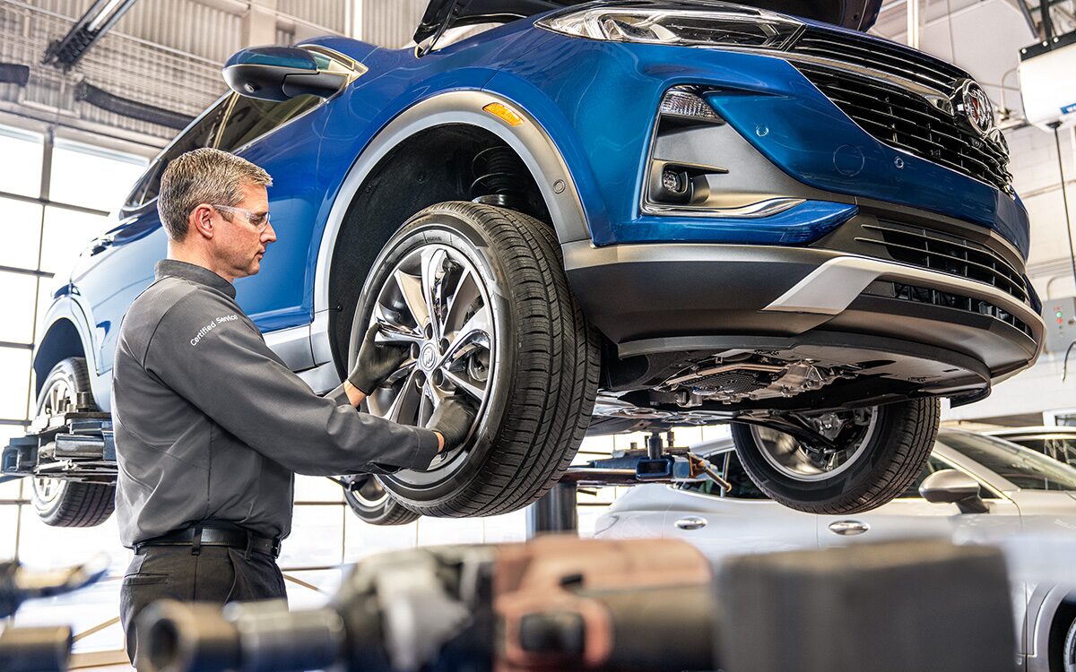 A Technician Is Inspecting the Wheel of a Blue Vehicle While Its Suspended in the Air