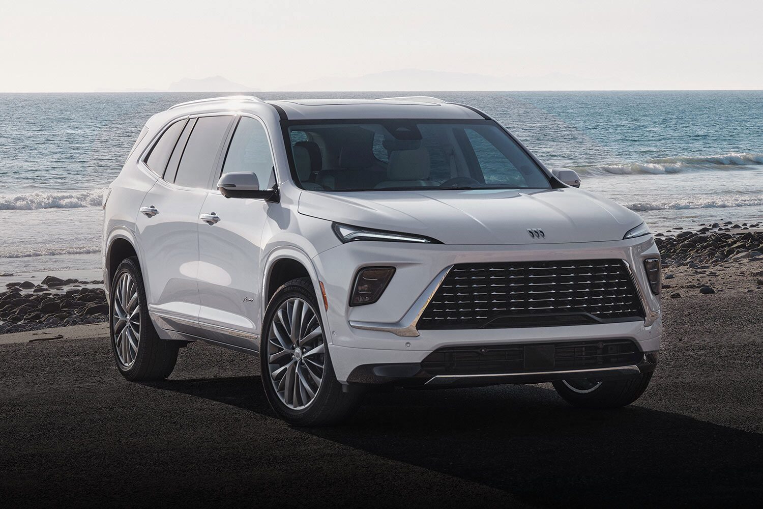 A White Buick Enclave Avenir SUV Driving on a Coastal Road Next to the Ocean