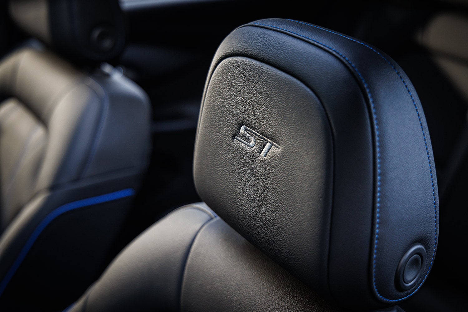 A Close-Up of a Black Leather Car Seat Headrest with Blue Stitching and an ST Emblem