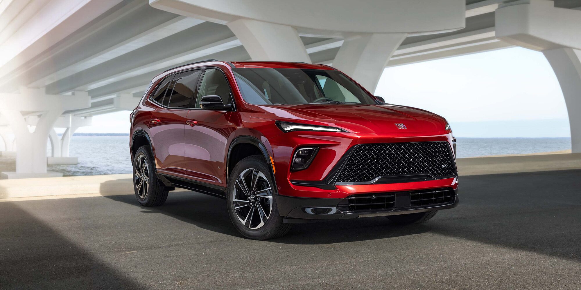 Three Quarters View of a 2026 Red Buick Enclave Parked under a Bridge