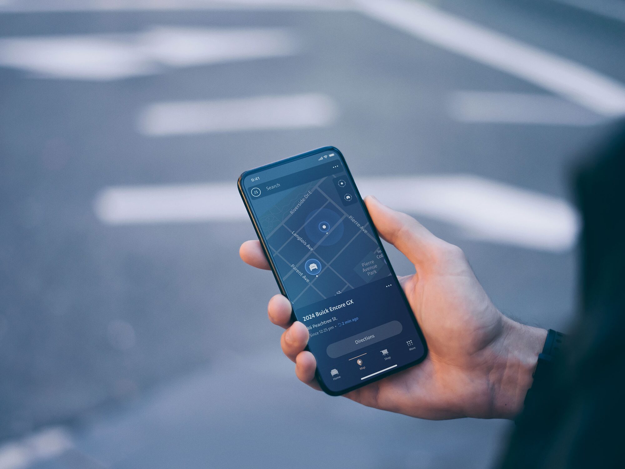 Close-up View of a Man Holding a Smartphone that is Displaying the GMC Mobile App