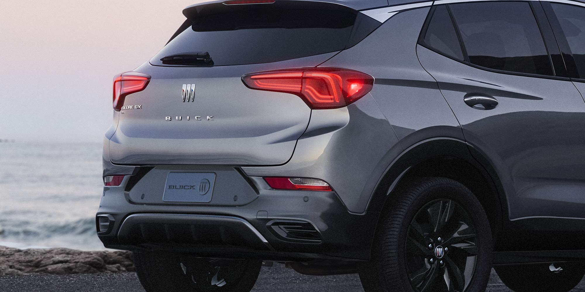 Back-side view of the 2026 Encore GX ST parked alone by the beach.