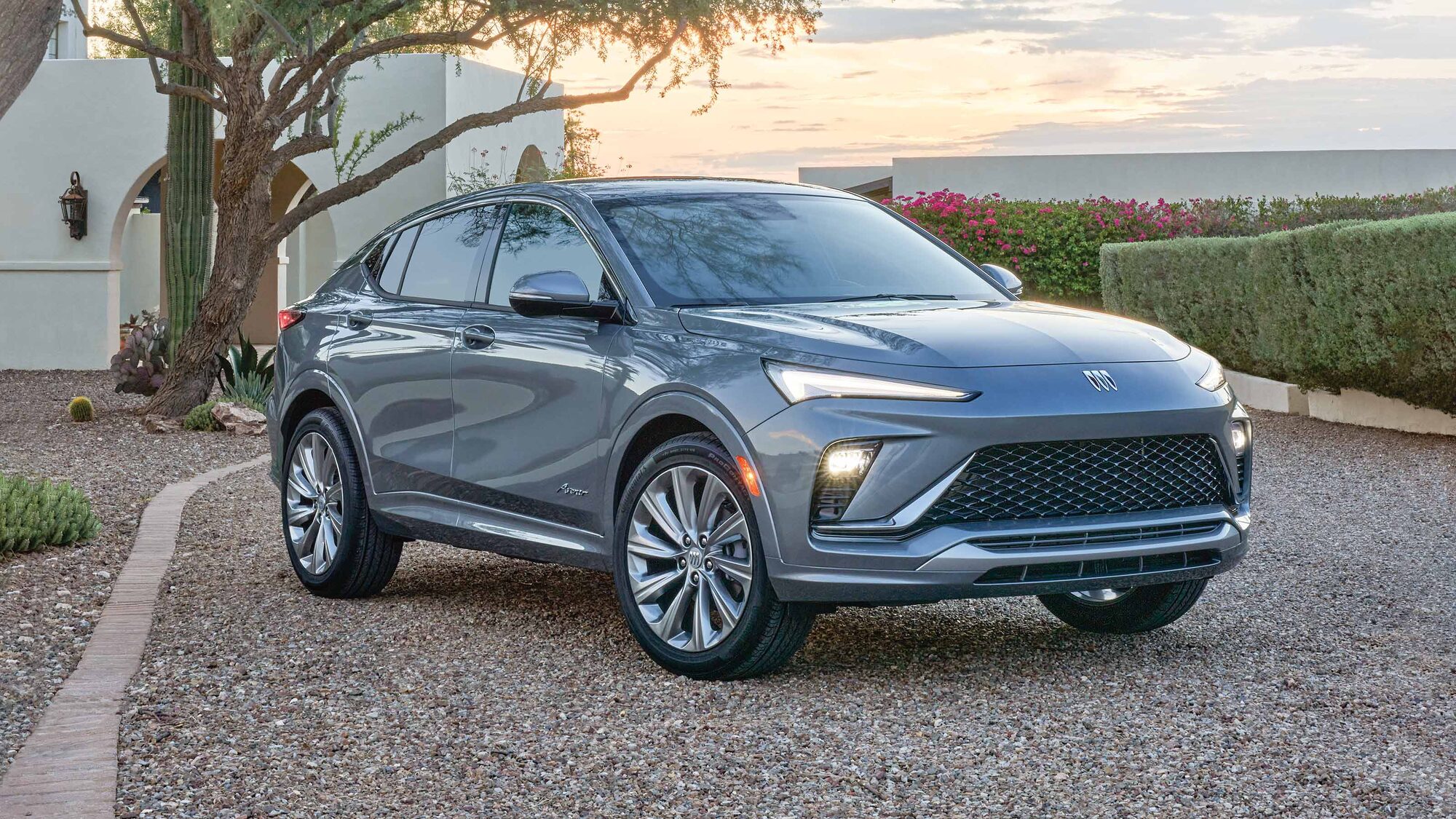 Three-quarters Passenger View of the 2026 Buick Envista Parked in a Gravel Driveway with the IntelliBeam Auto High Beams On