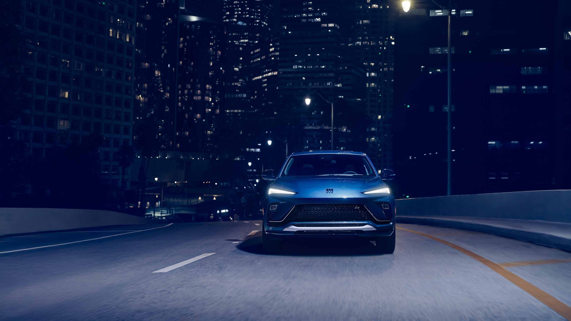 The 2026 Buick Envista Sport Touring Driving Out of the City Under a Street Light