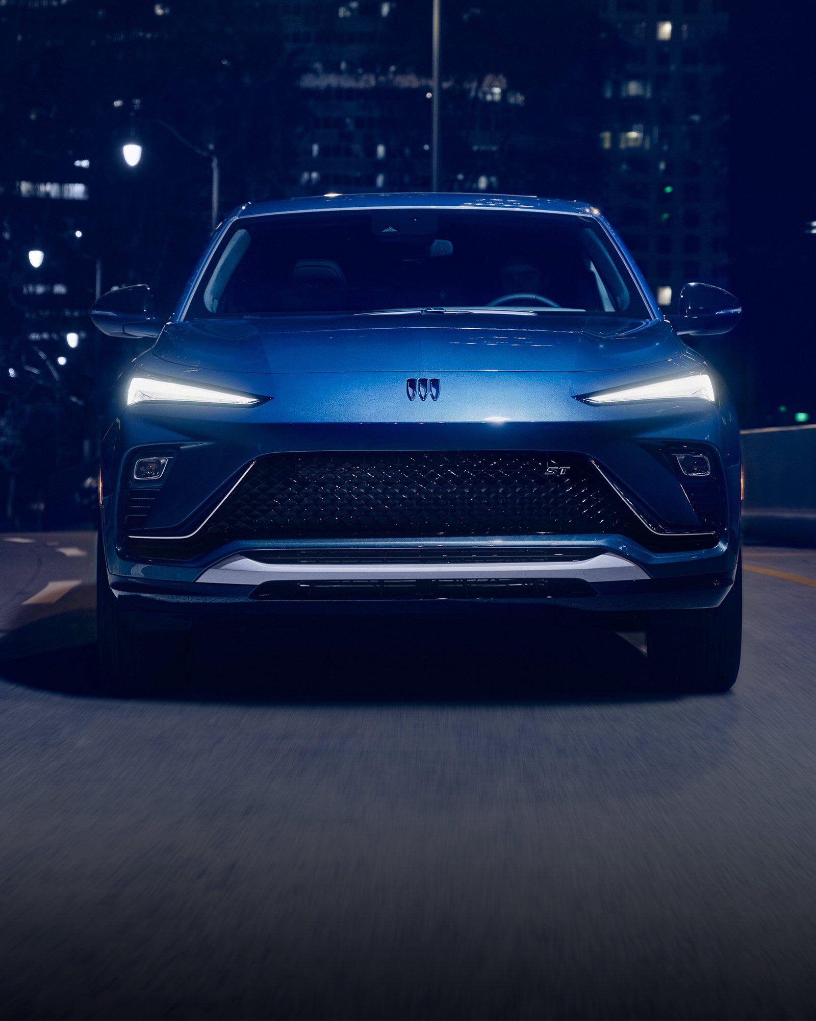 The 2026 Buick Envista Sport Touring Driving Out of the City Under a Street Light