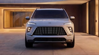 La vue de face d’un VUS blanc Buick Enclave Avenir 2027 stationné devant un bâtiment moderne