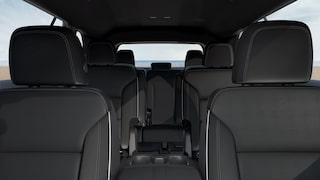 Un intérieur Buick Enclave 2027 avec trois rangées de sièges en cuir noir et une vue sur l’océan.