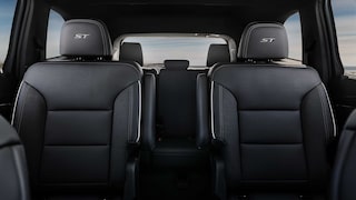 Vue intérieure de la deuxième rangée de sièges de la Buick Enclave ST 2027 avec deux chaises de capitaine gris foncé et la broderie « ST ».