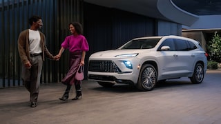 Un couple se tenant la main et s’éloignant d’un VUS Buick Enclave blanc 2027 stationné à l’extérieur